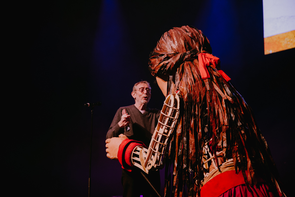 Little Amal goes to hug Michael Rosen whilst on stage at the Roundhouse.