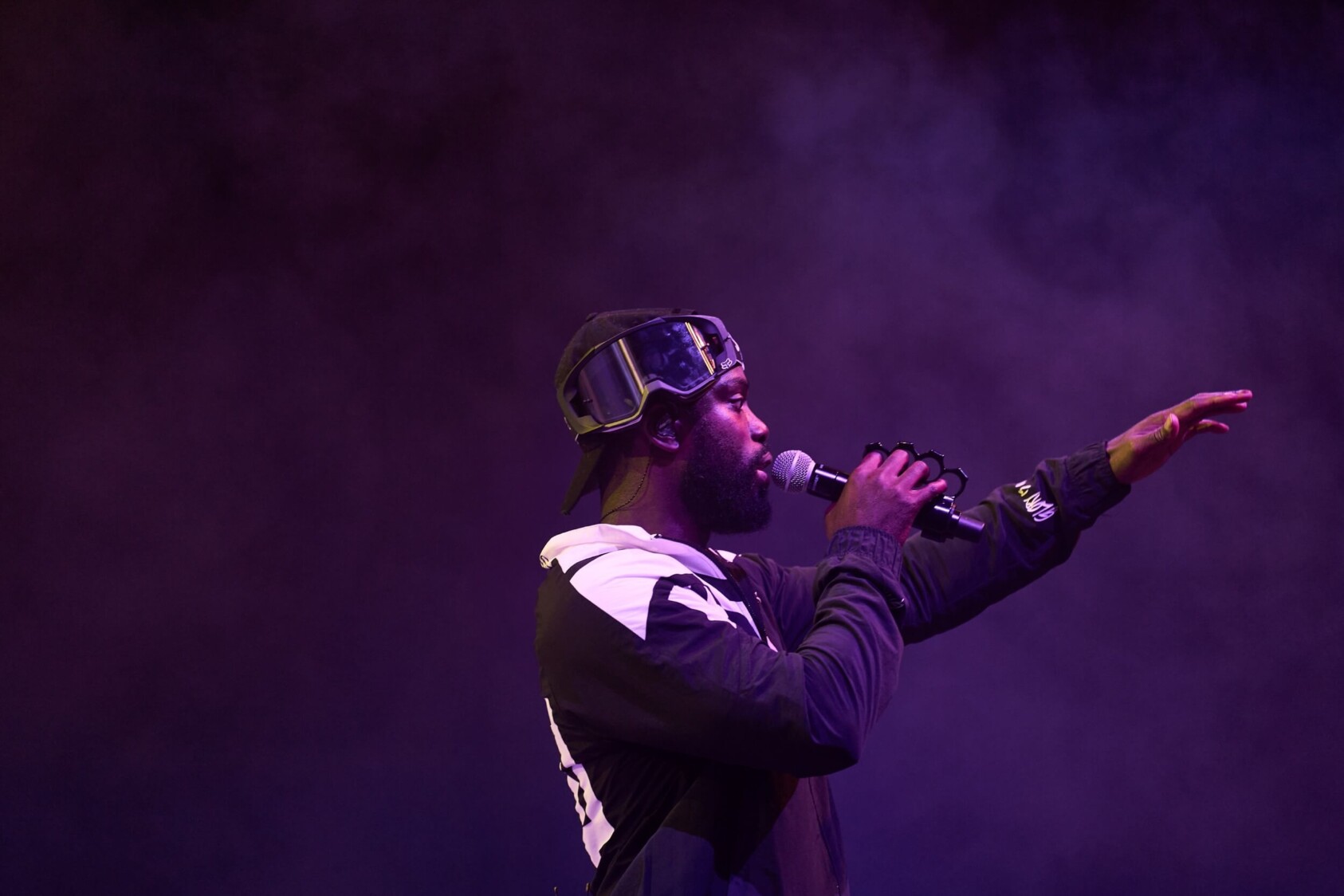 Ghetts performs on stage with a microphone in his hand and looking out to the crowd.