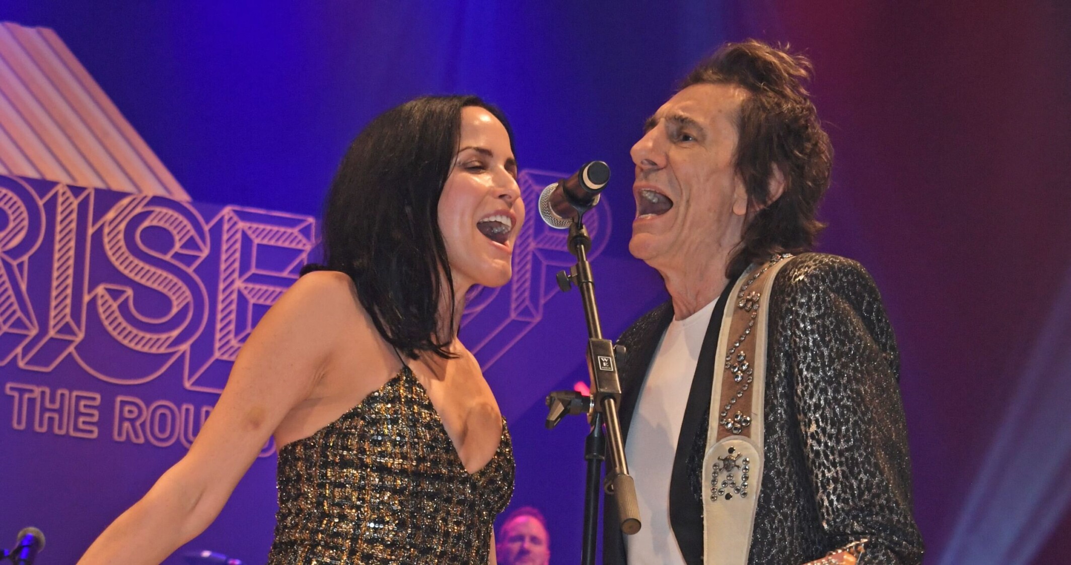 Andrea Corr and Ronnie Wood both sing into the same microphone whilst Ronnie plays the guitar.