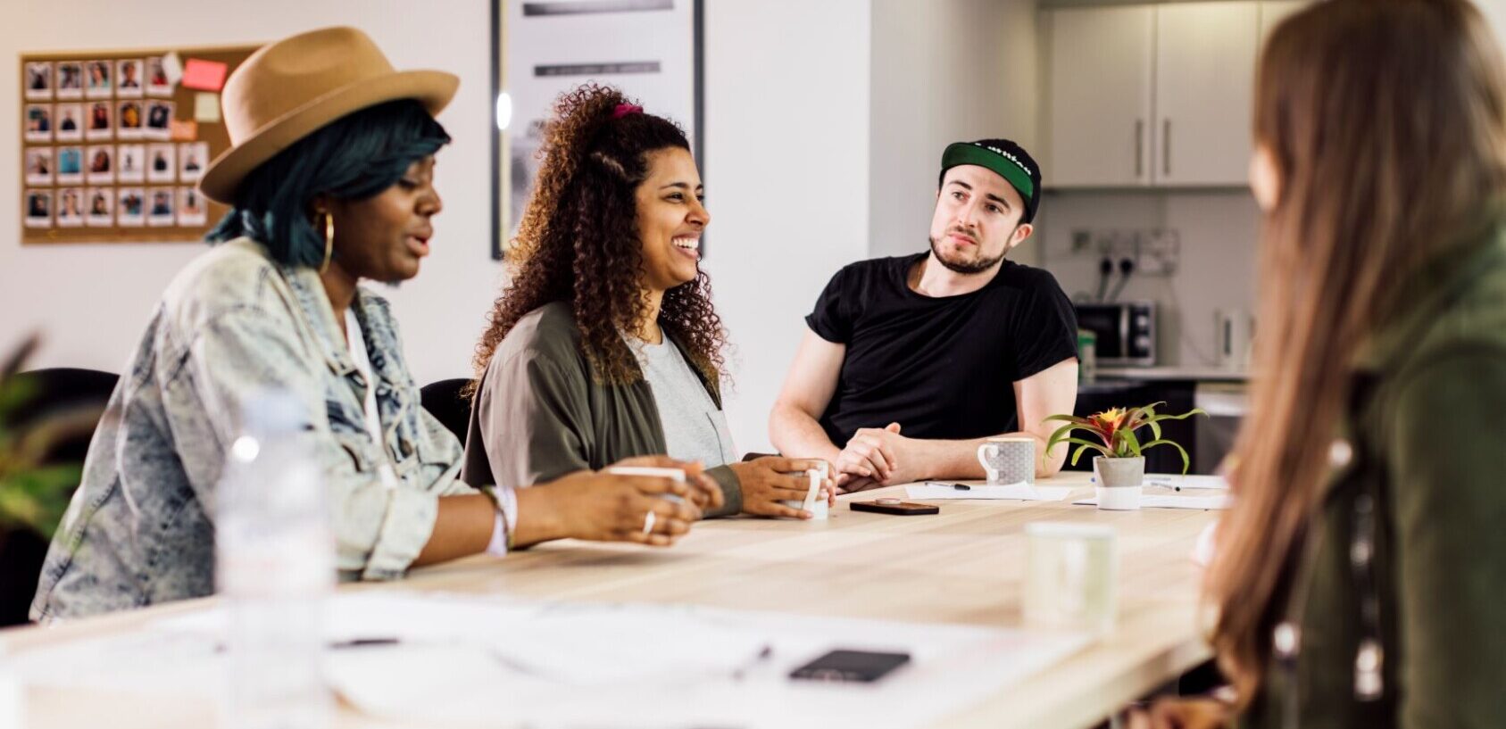 Young entrepreneurs and freelancers sit around a table in an office space chatting to each other.