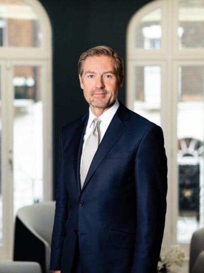 Simon Turner smiles at the camera for his headshot whilst wearing a blue suit.