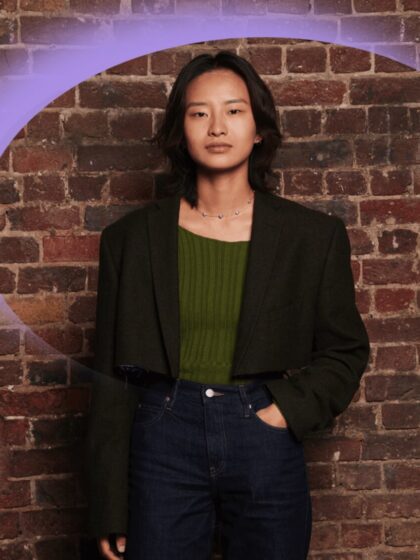 Chen, the winner of the Self-Made Accelerator programme, stands in front of a brick wall wearing jeans, a green top and a dark jacket. There is a purple crescent graphic over the image.