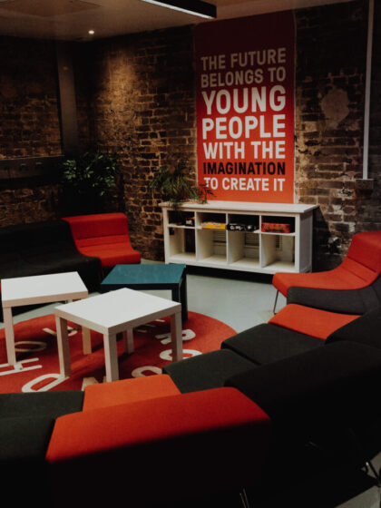 A room with red and black chairs with a sign in the background saying 'The future belongs to young people with the imagination to create it'