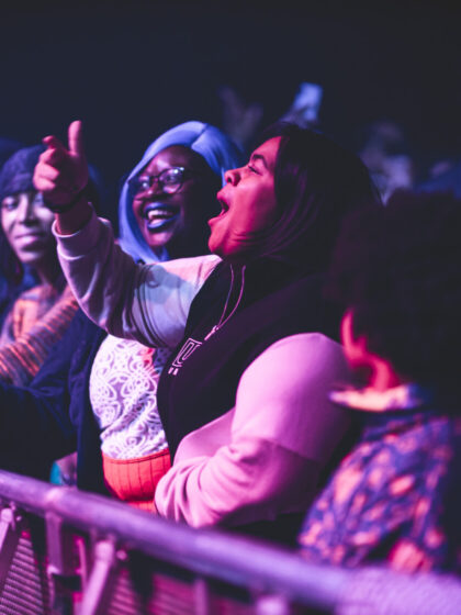 Women in a crowd smiling as they watch a performance