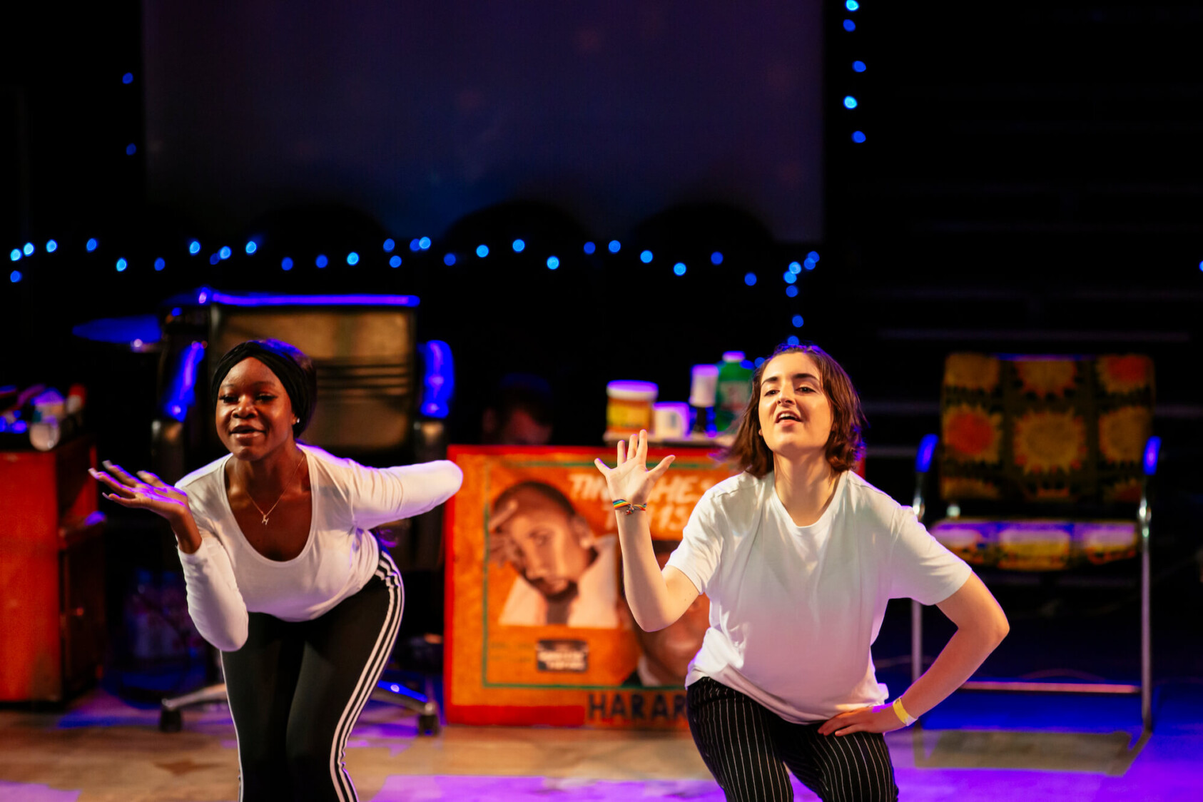 Two girls in white t shirts dance and wave their right hands