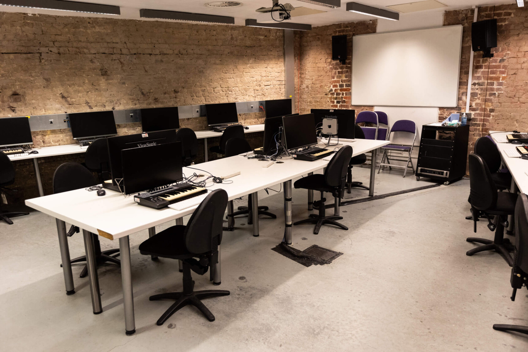 The interior of the New Media Lab which includes desks set up with mac computers and chairs