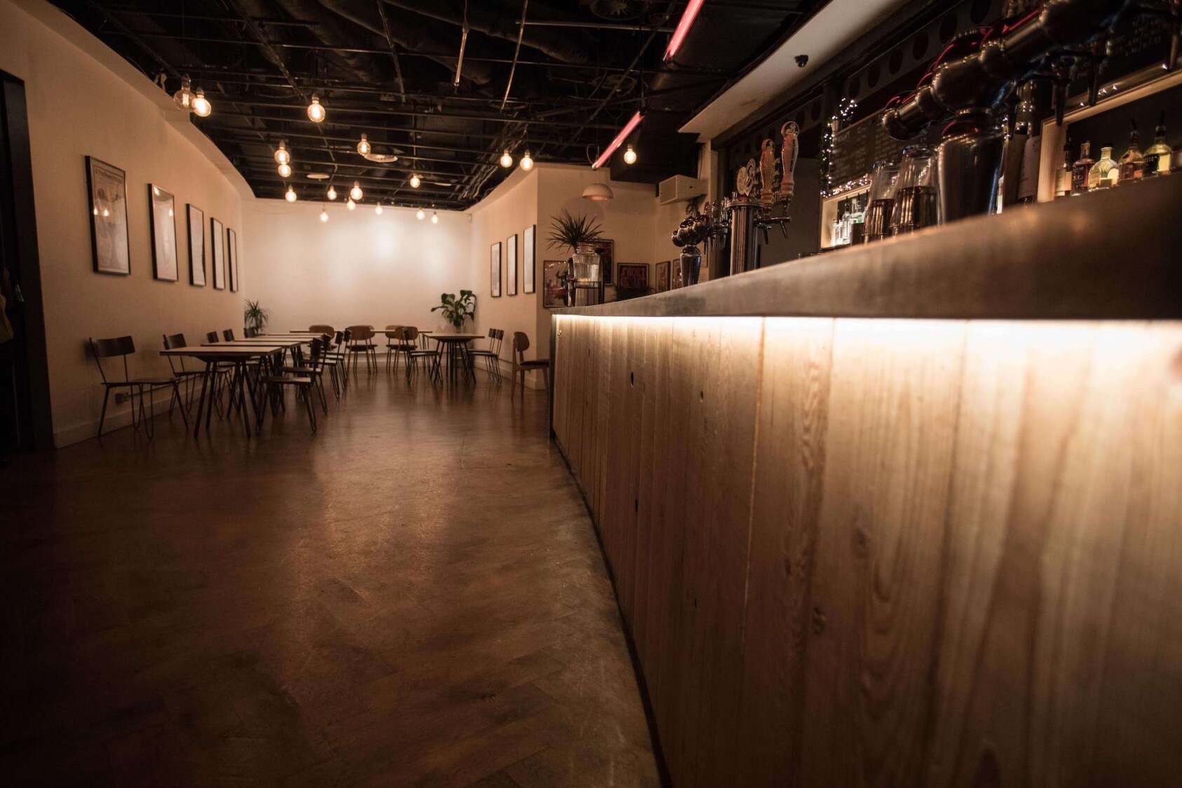 The interior of the RBC - a long concrete bar lit with soft light with chairs and tables in the distance