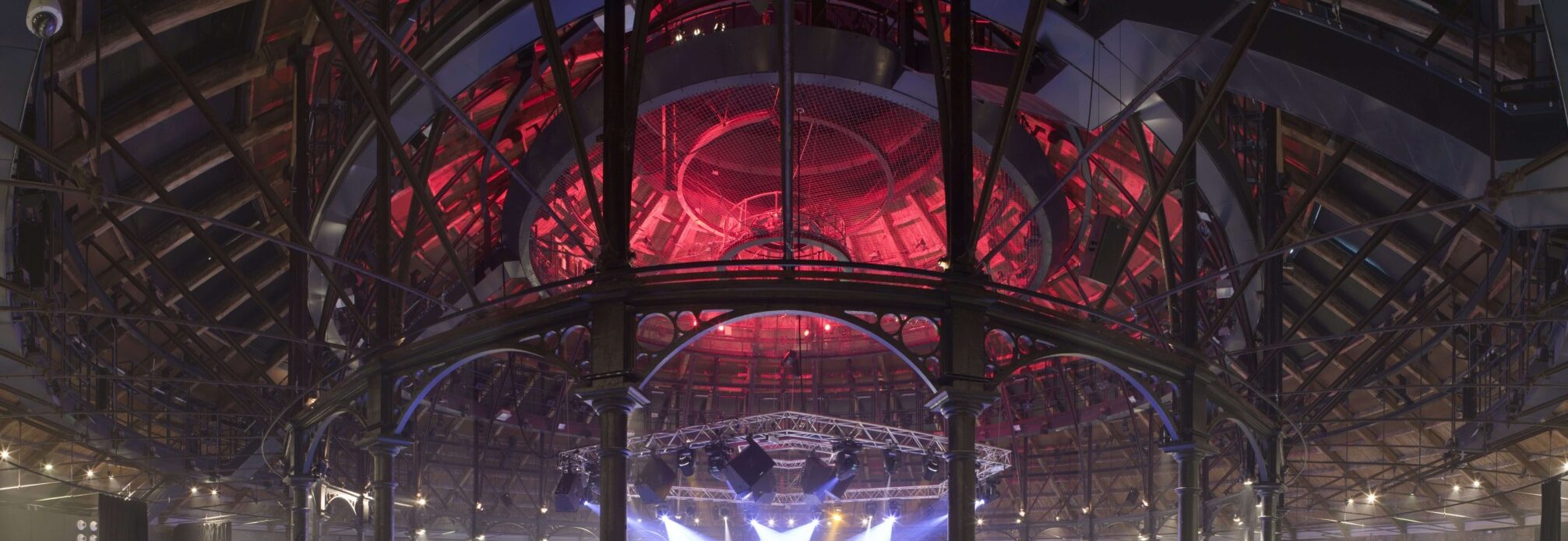 The main space of the roundhouse which is a large circular space lit up purple and red