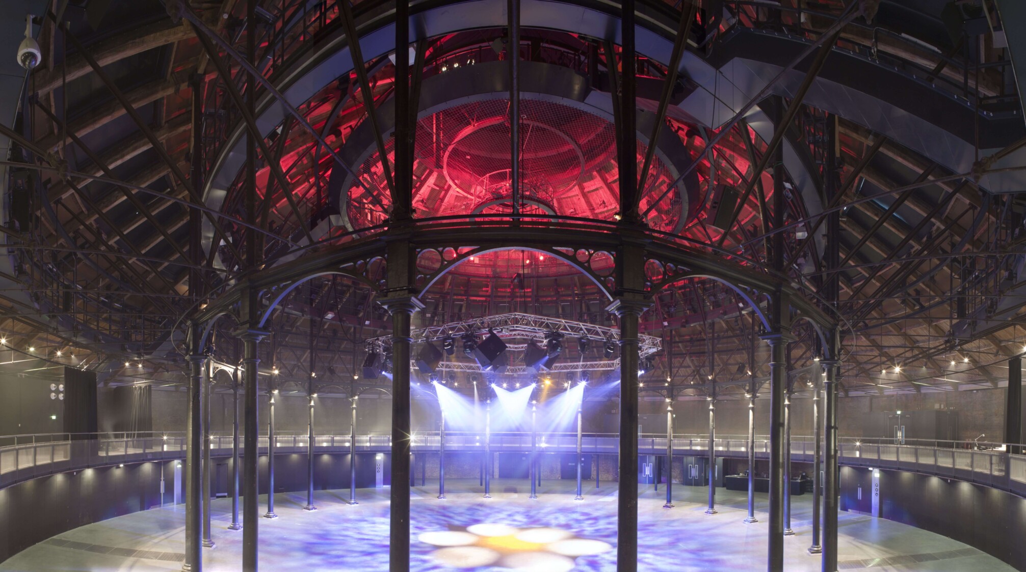 The main space of the roundhouse which is a large circular space lit up purple and red