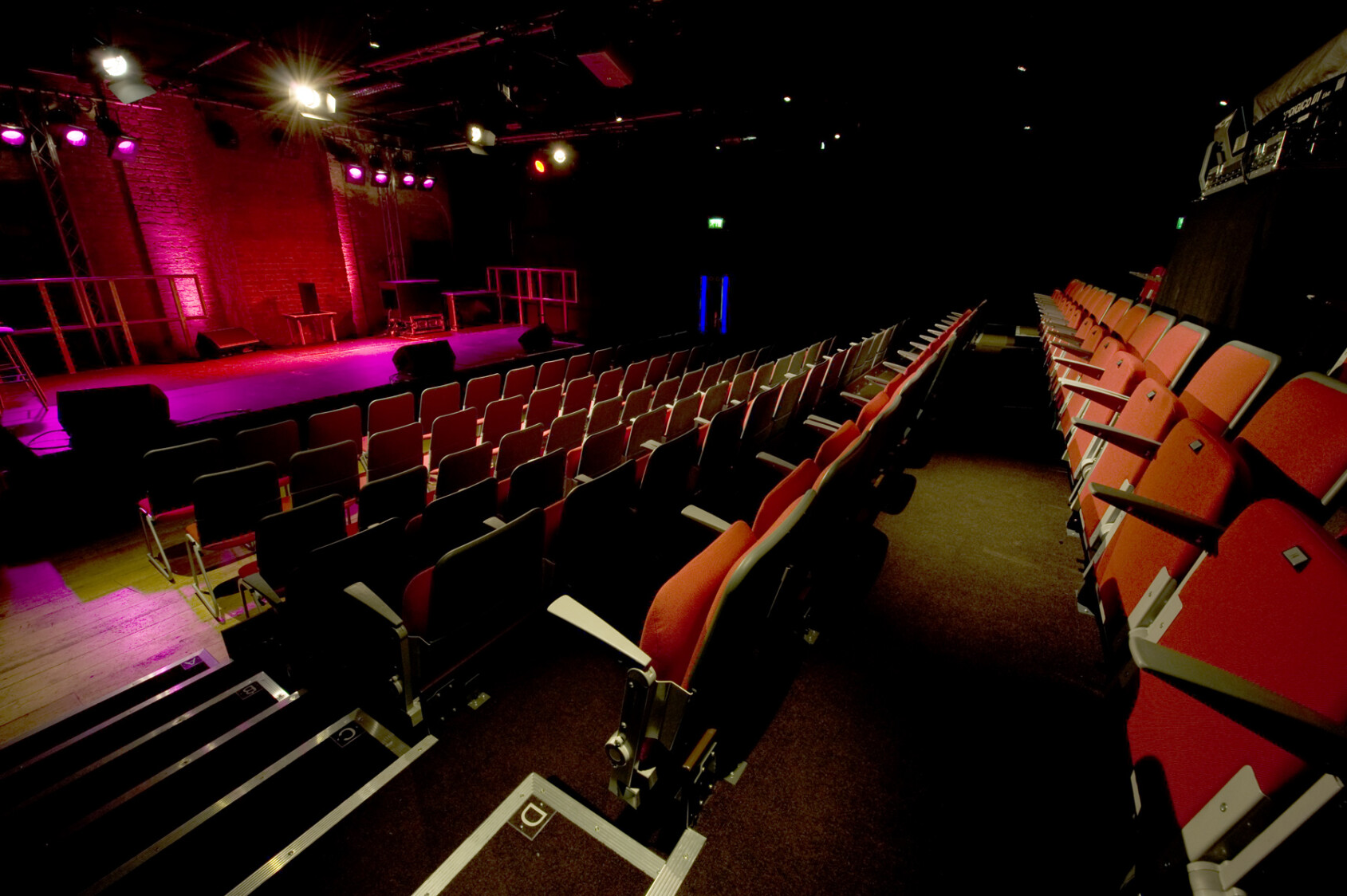 The inside of the Studio Theatre - lit with pink light and rows of red seats