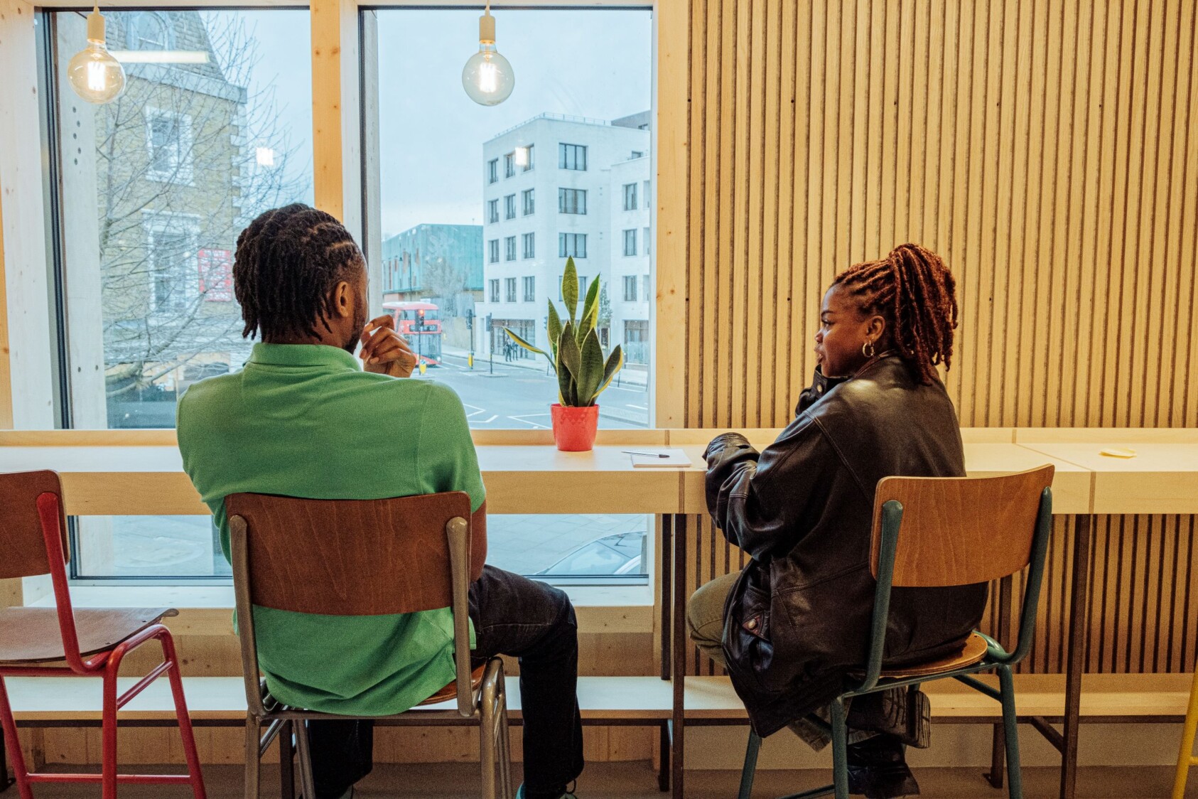 two people at at desk space by a window