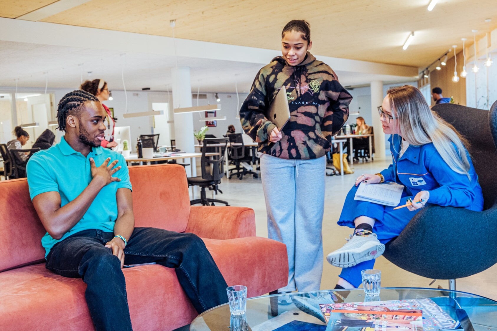 three people sitting around sofas chatting