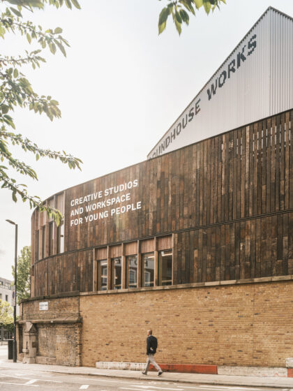 The outside of Roundhouse Works which includes an exposed brick wall, wooden cladding and a metal structure with a person walking in front.