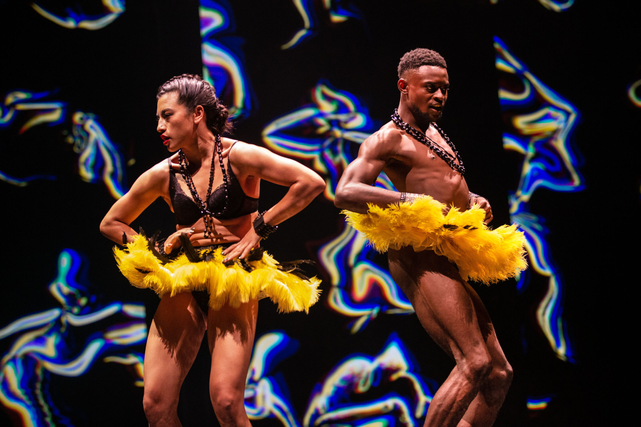 Two dancers perform wearing bright yellow feathered tutu's that resemble bananas