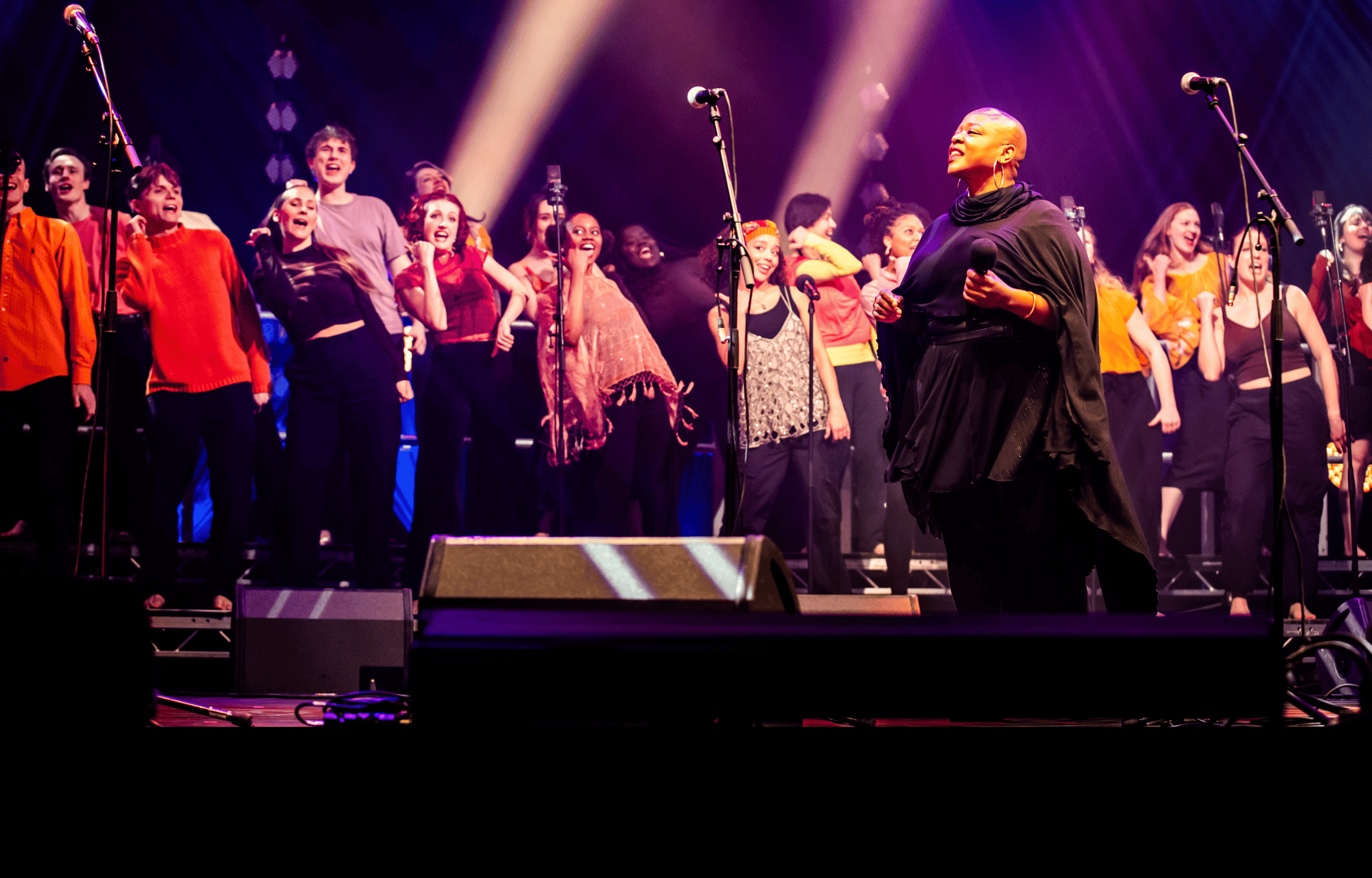 ESKA performing with the Roundhouse Vocal Ensemble on stage at the Roundhouse. Joyful dancing and singing.