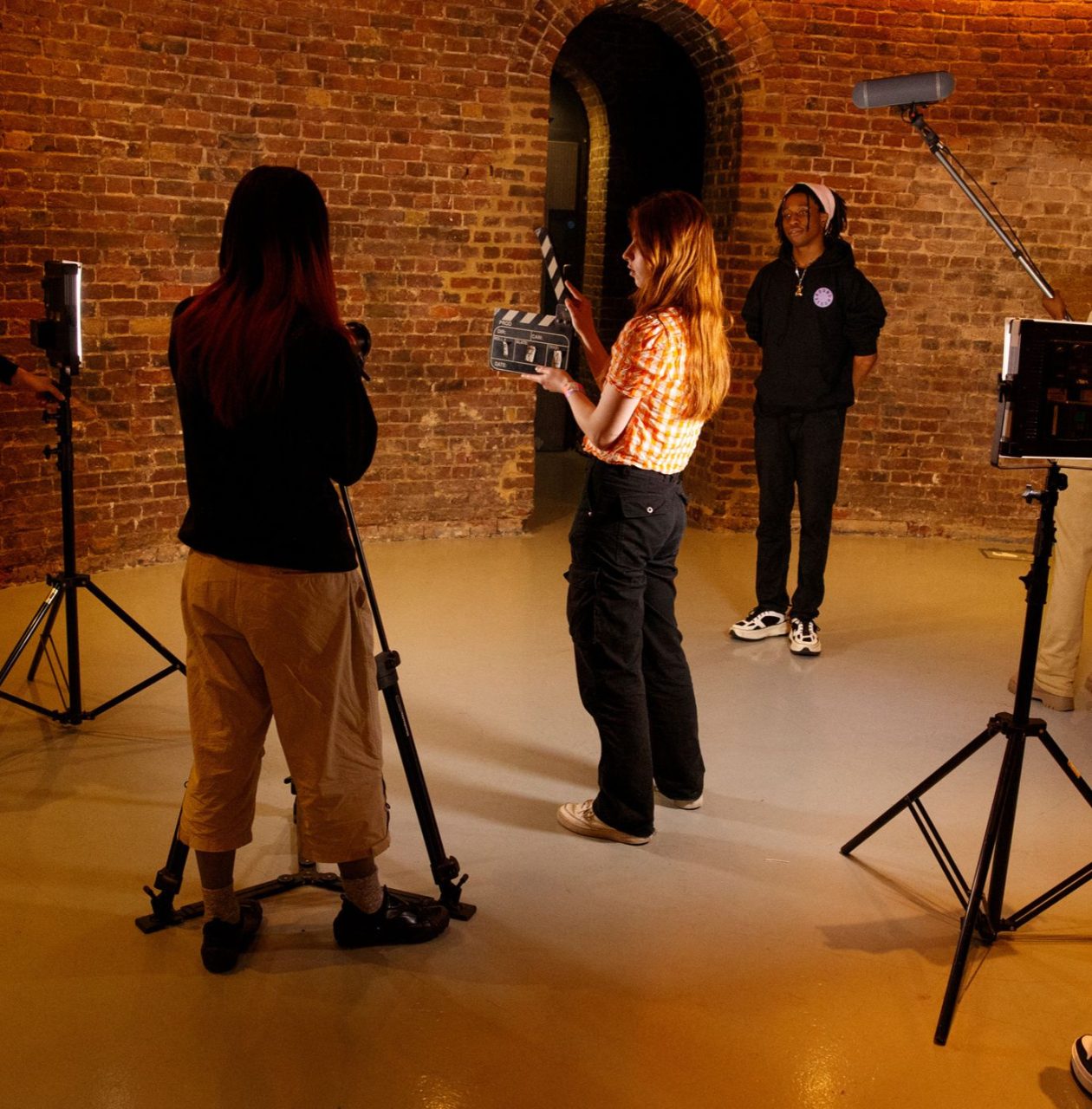a group of 5 young people on a film set with lighting and cameras