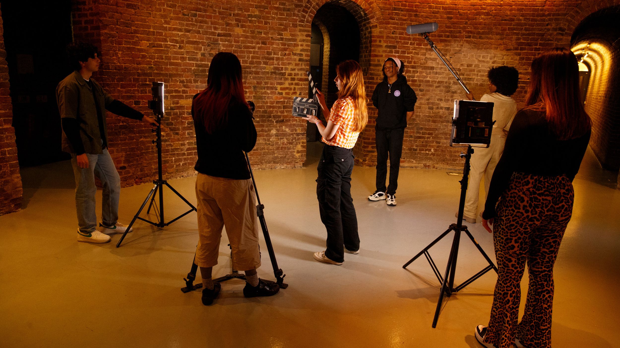 a group of 5 young people on a film set with lighting and cameras
