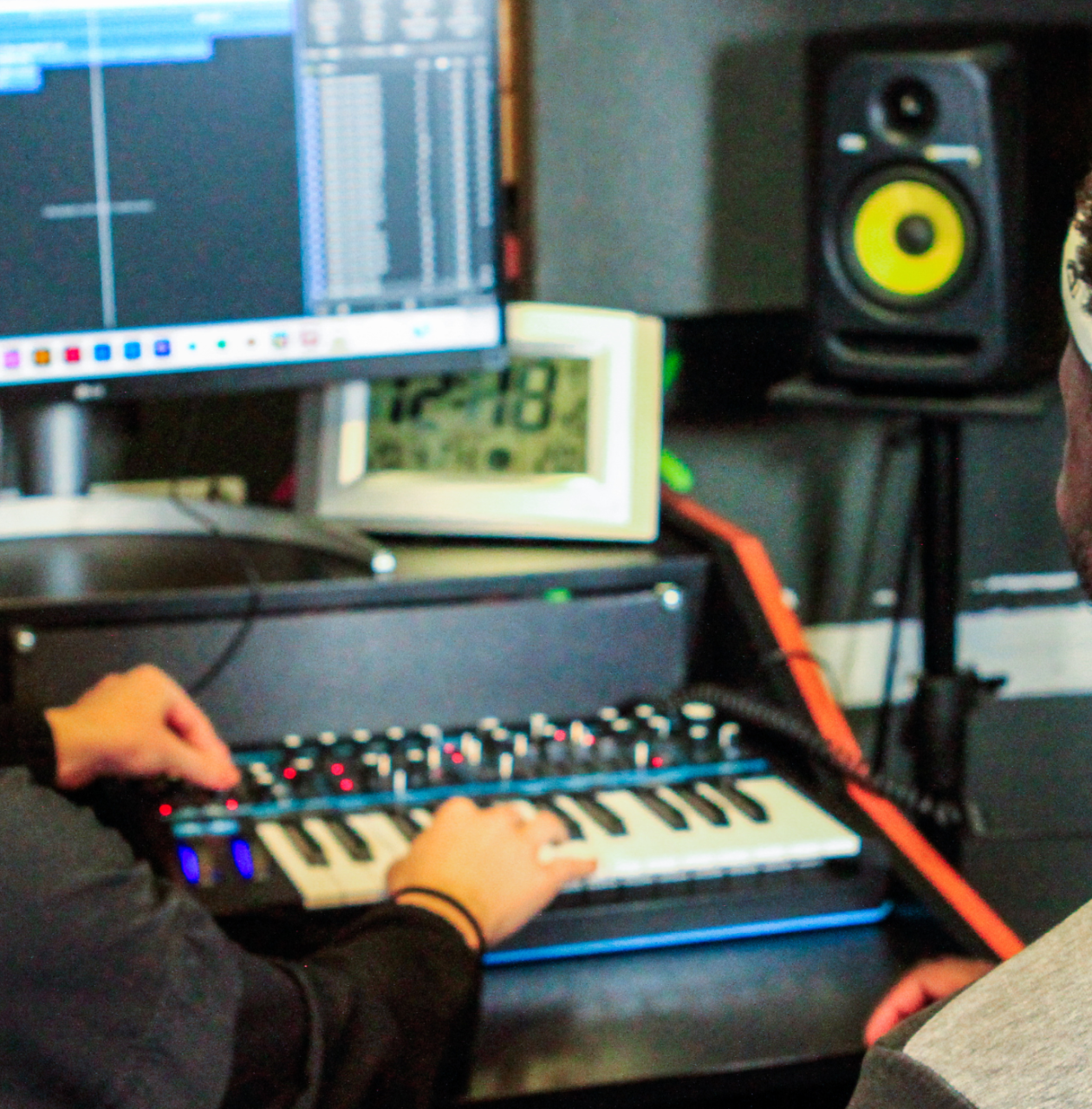 Tutor guiding younger producer and teaching him how to use software