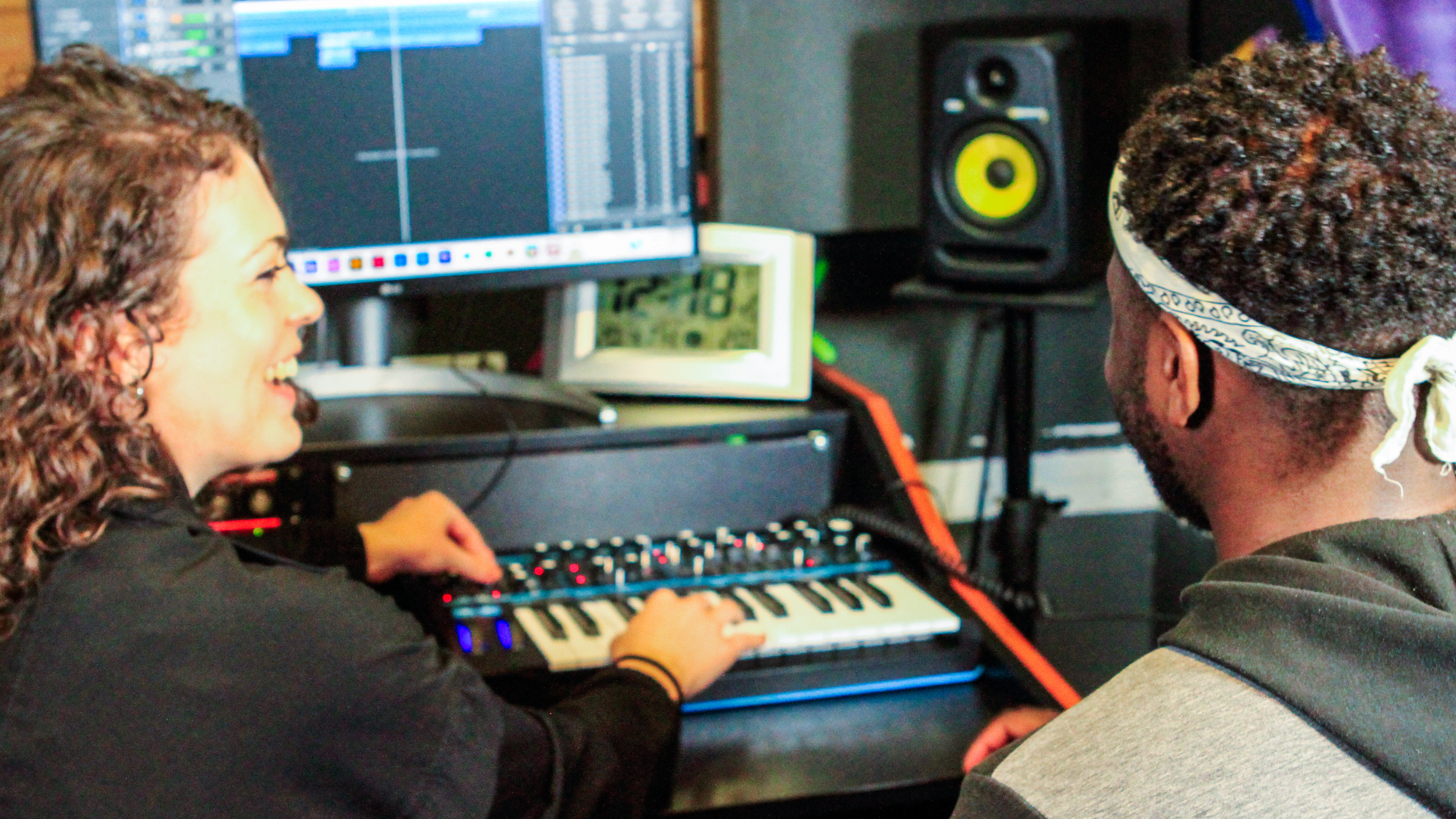 Tutor guiding younger producer and teaching him how to use software