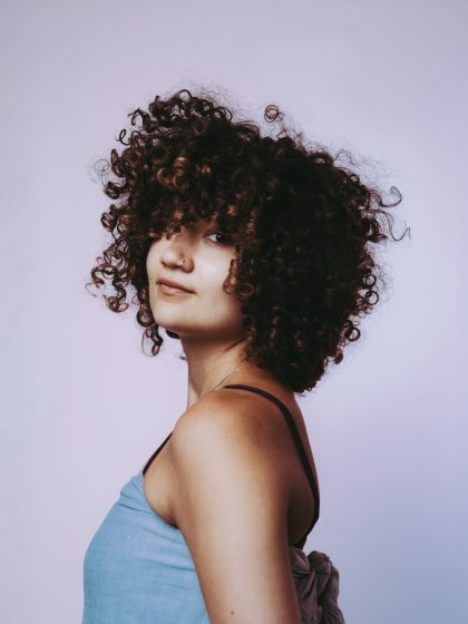 a young person with dark skin, dark brown afro wearing a blue top