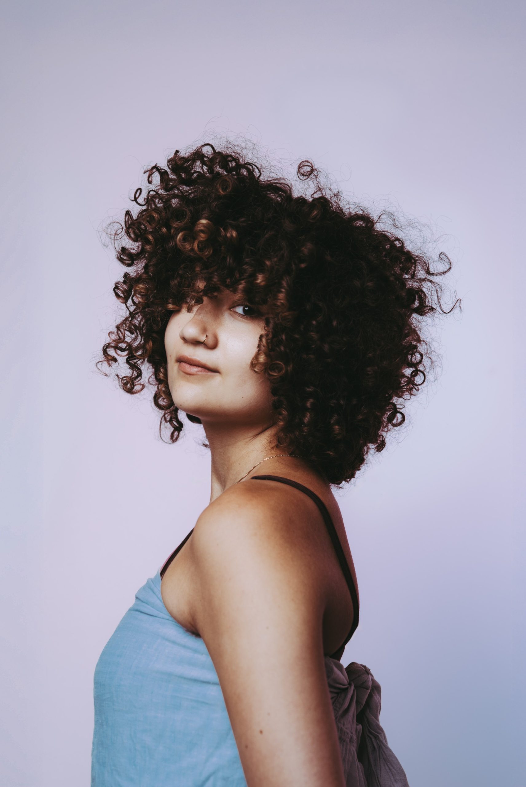 a young person with dark skin, dark brown afro wearing a blue top