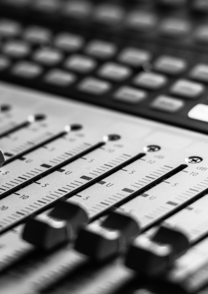 Close-up of an audio mixing console with sliders and buttons.