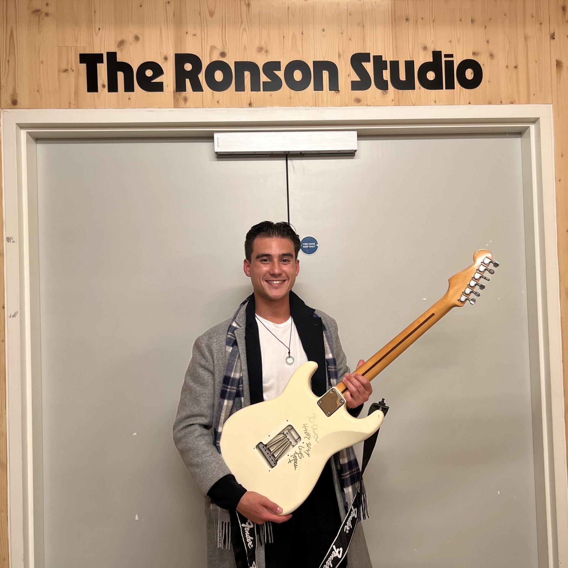 Owen Walters poses with a white guitar with a gold signature on it.