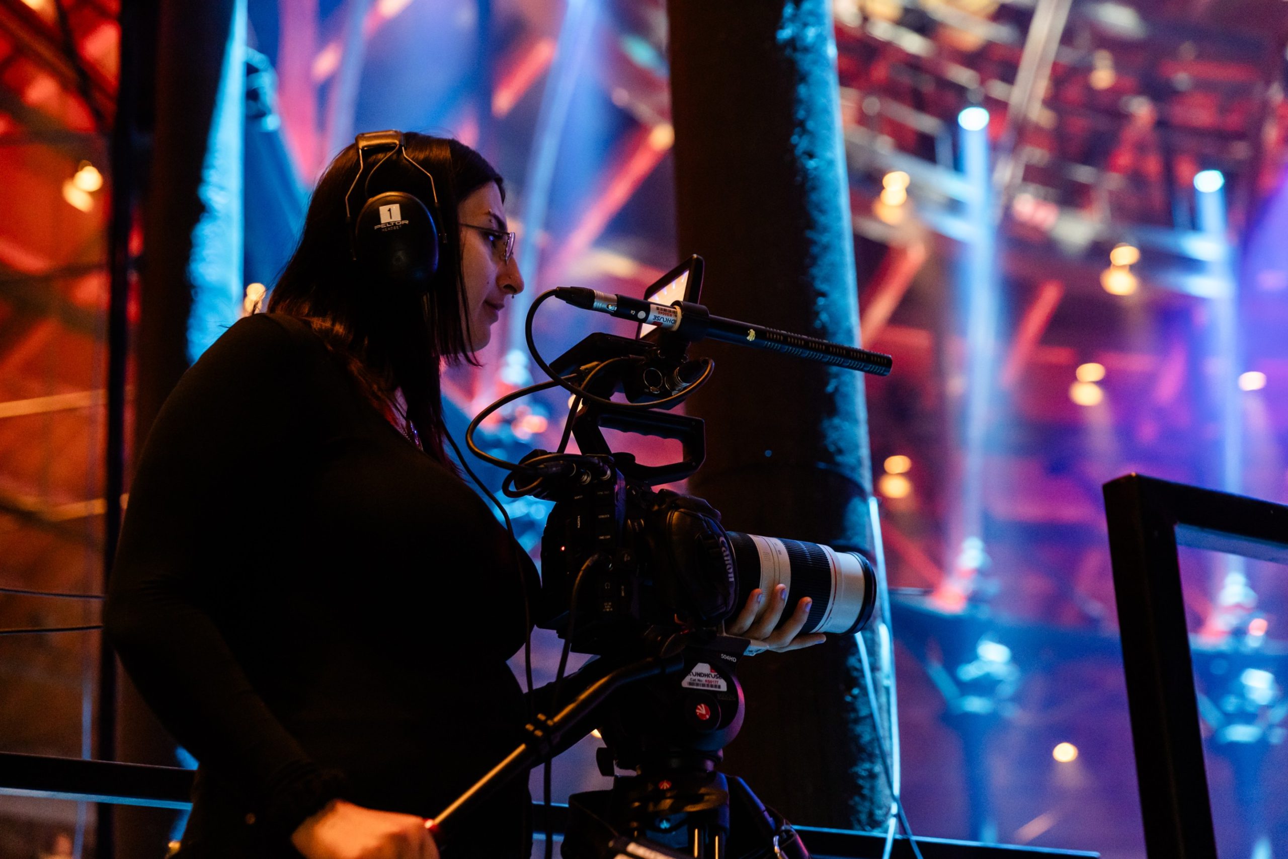 A young person operates a camera in front of a blue and red background