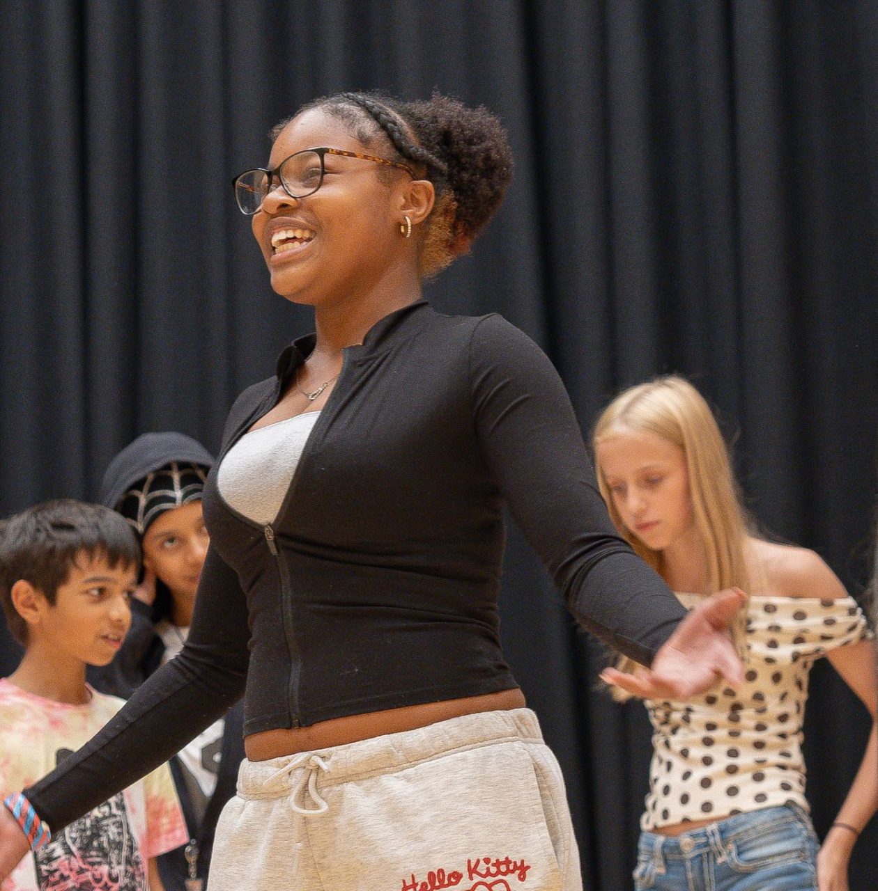 A group of young people performing drama with a dark curtain backdrop