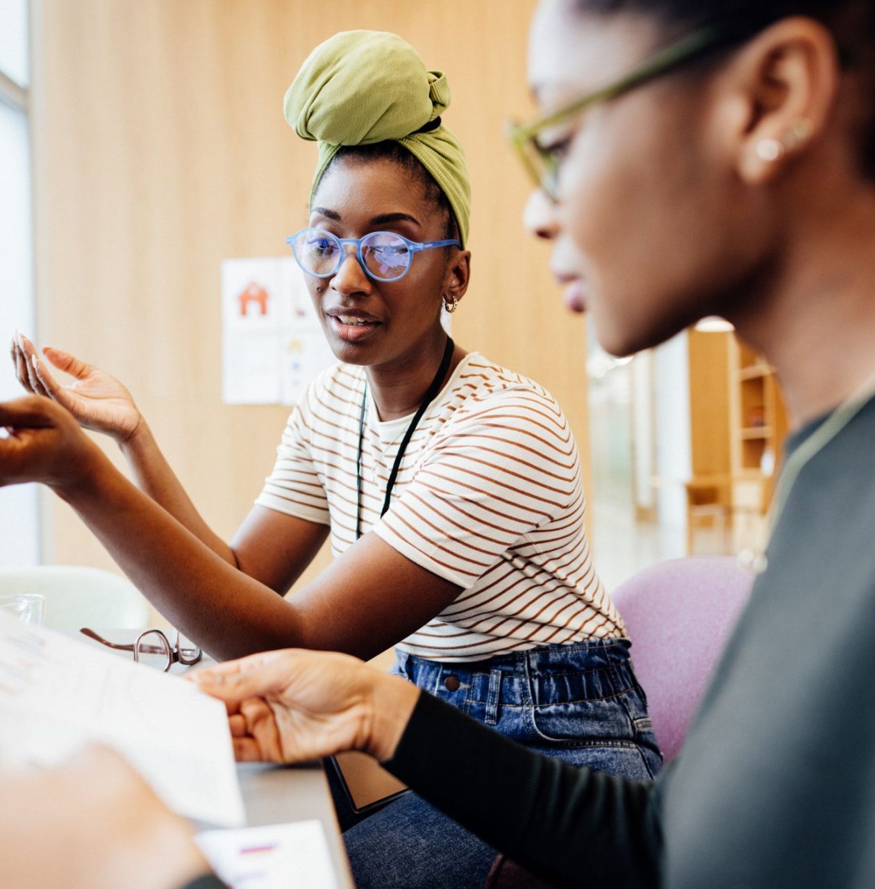 Two people, one wearing glasses, look together at a computer screen or document in an office setting.