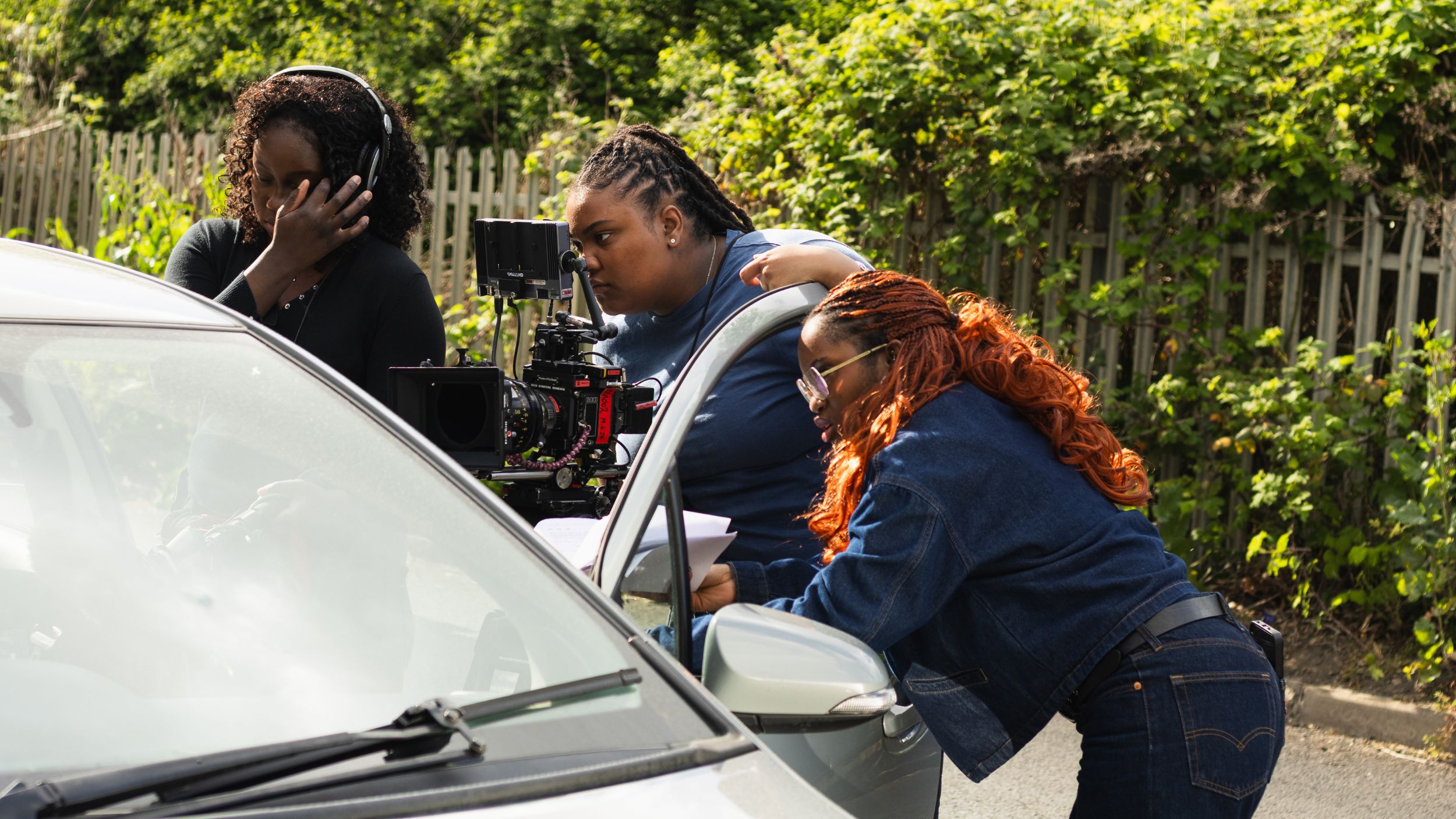 three young people holding film cameras on a set